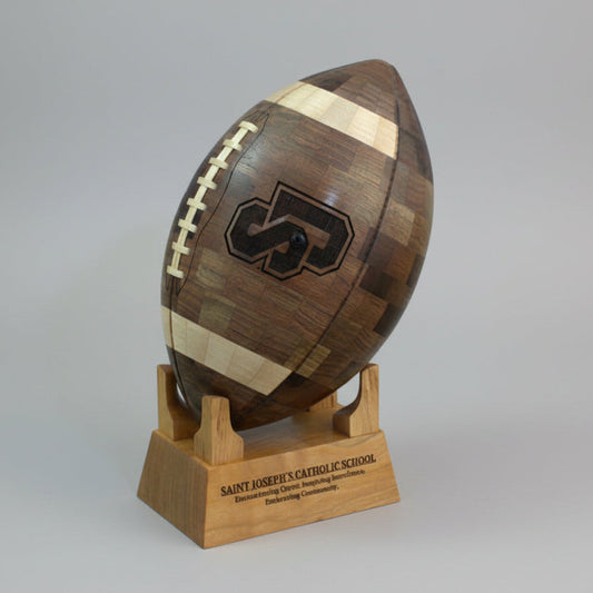 Wooden football sculpture with a logo on a stand against a gradient background